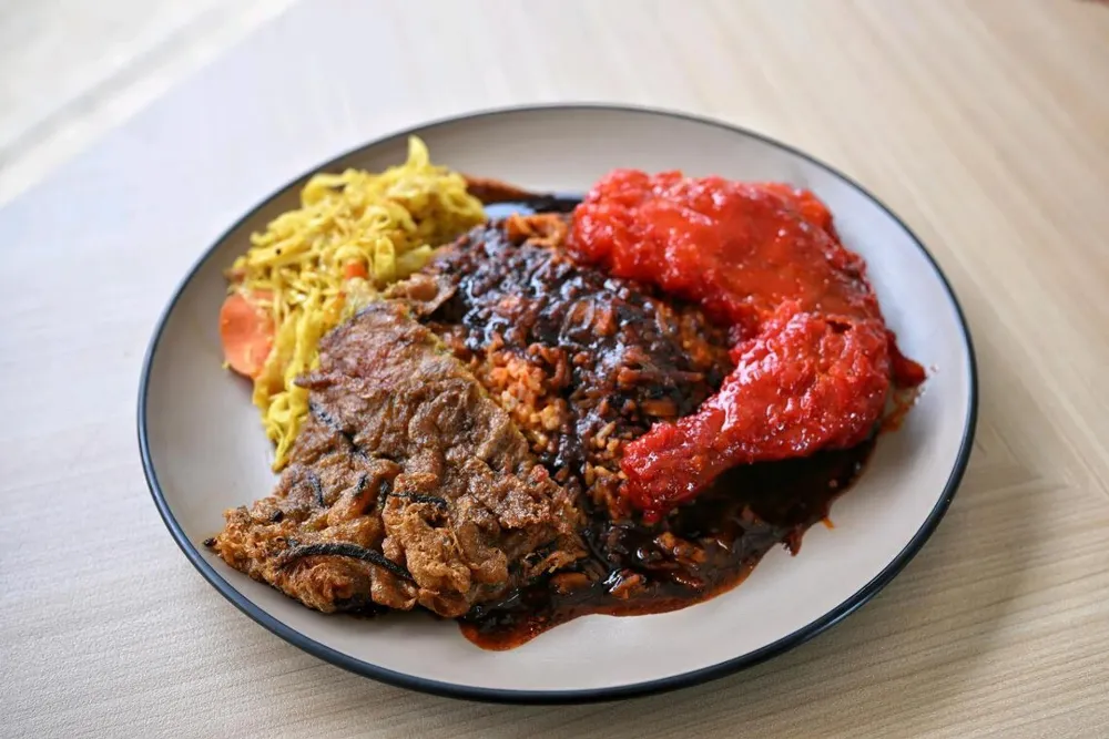 Meal Ayam Madu at Yaseem — honey chicken in red sambal with mee goreng, dark masak hitam gravy and rice on a black-rimmed plate