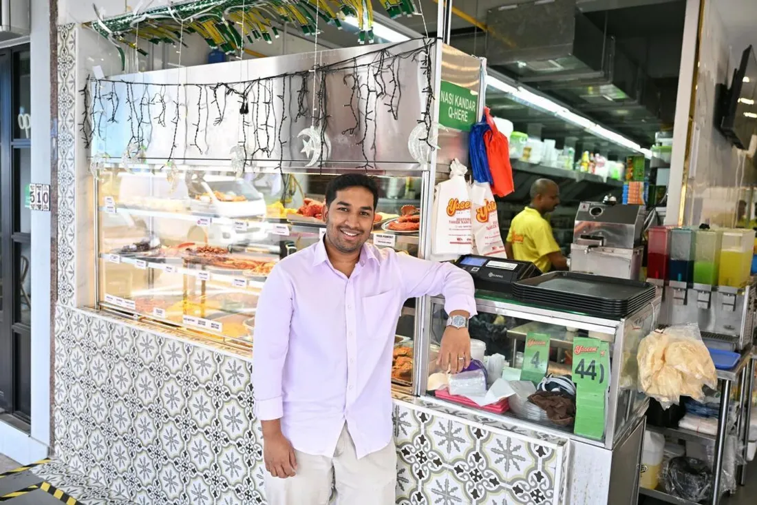 Co-owner Muhamad Afzal at the Yaseem Nasi Kandar service counter on MacPherson Road, a colleague in the yellow Yaseem polo working behind him
